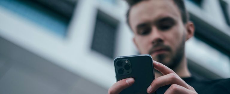 Nuori mies katselee älypuhelintaan. Kuva: Jonas Leupe.